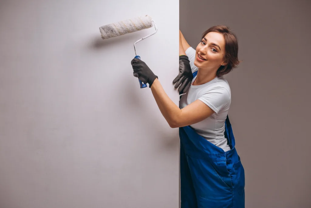 woman-repairer-with-painting-roller-isolated A girl with a painting roller smiling towards the camera